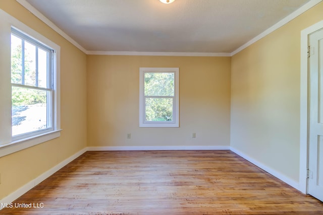 unfurnished room with light hardwood / wood-style floors, ornamental molding, and a wealth of natural light