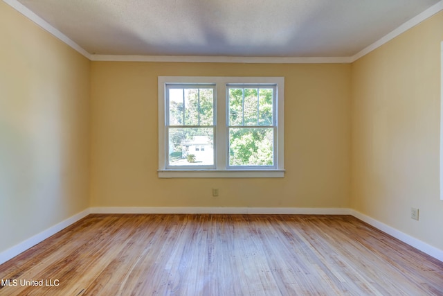 spare room featuring ornamental molding and light wood-type flooring