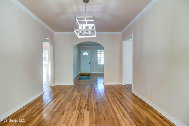 entrance foyer with a notable chandelier, wood-type flooring, and ornamental molding