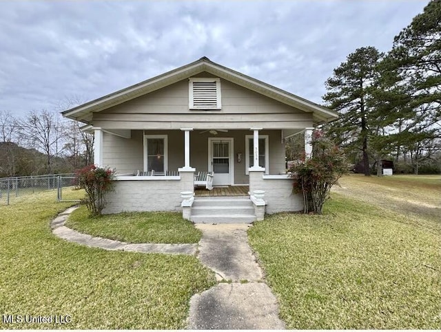 bungalow-style home featuring covered porch and a front yard