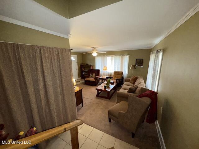 tiled living room featuring ceiling fan and crown molding