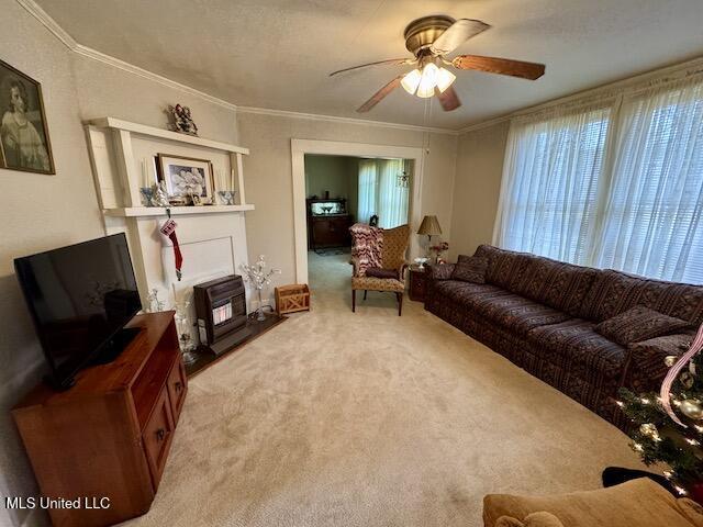 living room with ceiling fan, ornamental molding, light carpet, and a fireplace