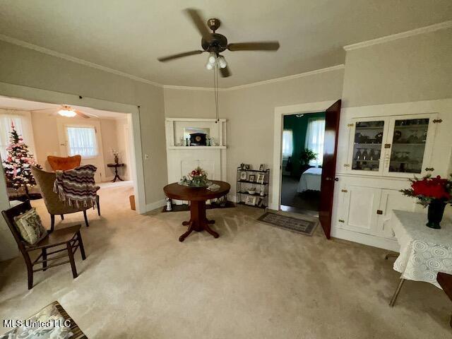 sitting room featuring ceiling fan, light colored carpet, and crown molding