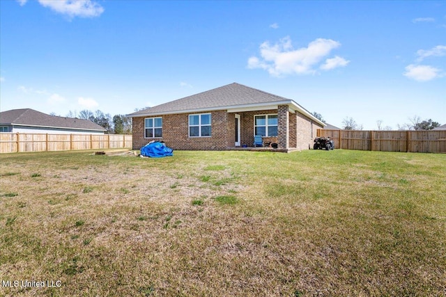 back of house with a lawn, brick siding, and a fenced backyard