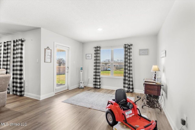 interior space with a textured ceiling, baseboards, and wood finished floors