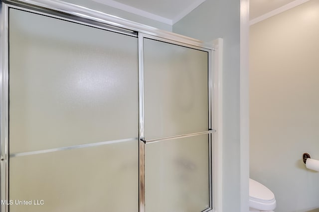 bathroom with toilet, a shower with door, and crown molding