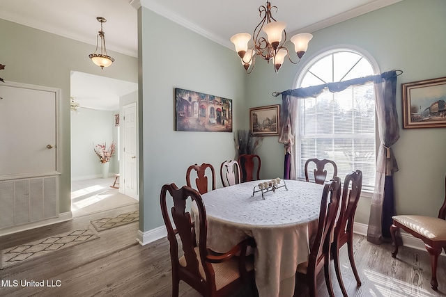 dining area featuring baseboards, visible vents, wood finished floors, crown molding, and a chandelier