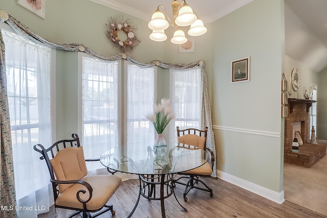 dining space featuring light wood-type flooring, a notable chandelier, baseboards, and crown molding