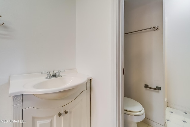 bathroom featuring toilet, baseboards, and vanity