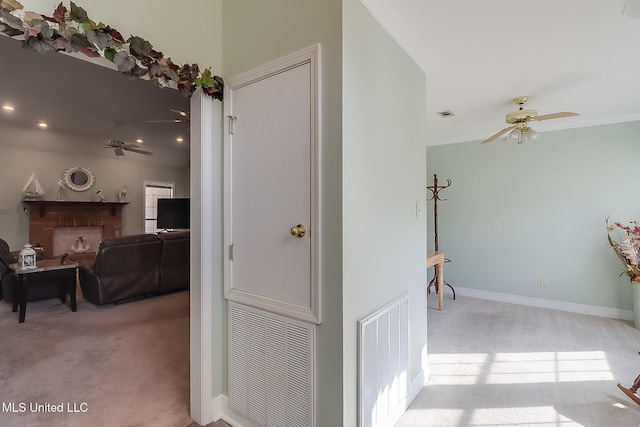 hallway with baseboards, visible vents, and light colored carpet