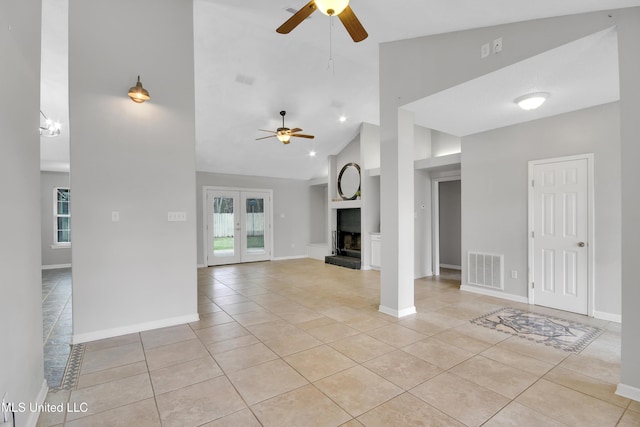 unfurnished living room featuring light tile patterned floors, visible vents, a fireplace with raised hearth, and ceiling fan