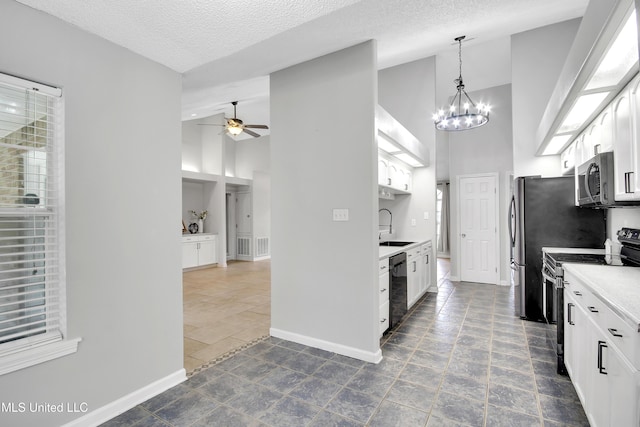 kitchen featuring ceiling fan with notable chandelier, a sink, white cabinetry, stainless steel appliances, and baseboards