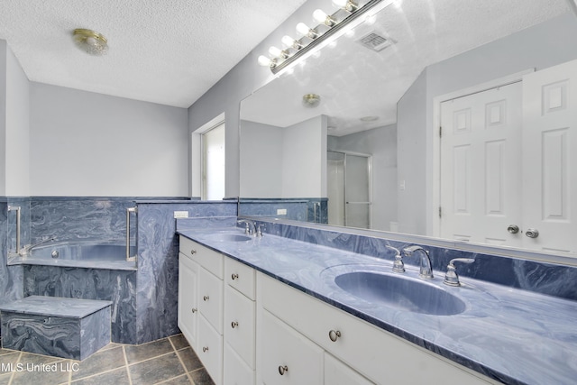 full bath with a textured ceiling, a shower stall, visible vents, and a sink