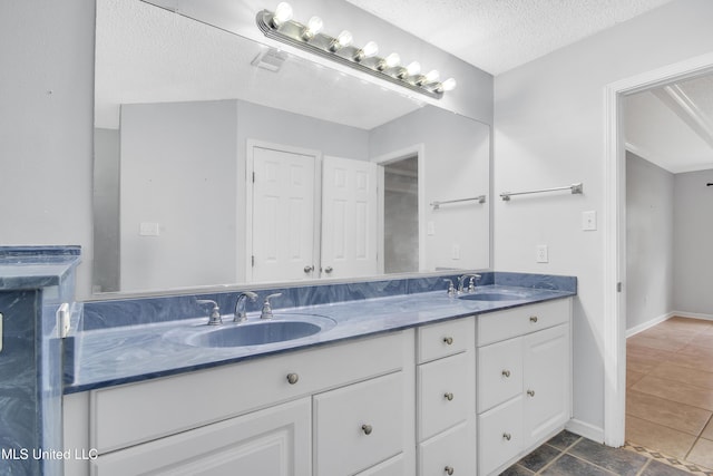 full bath featuring a sink, a textured ceiling, and double vanity