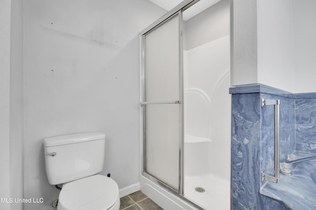 full bathroom featuring tile patterned floors, baseboards, toilet, and a shower stall