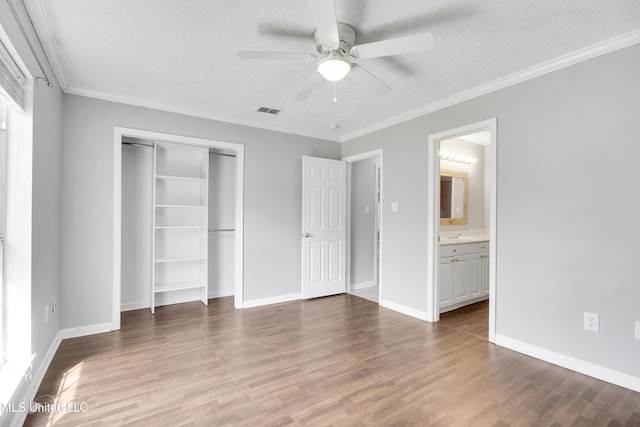 unfurnished bedroom featuring a closet, ornamental molding, a textured ceiling, and wood finished floors