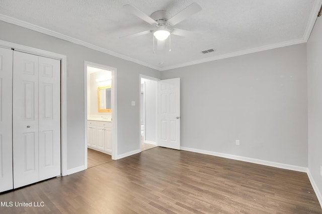 unfurnished bedroom with visible vents, ornamental molding, a textured ceiling, wood finished floors, and baseboards