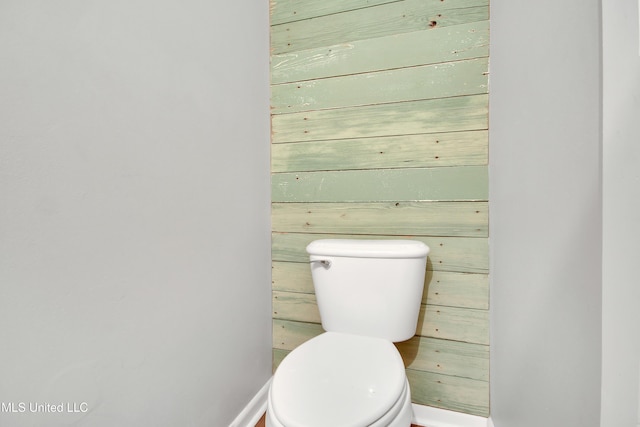 bathroom with toilet and wood walls