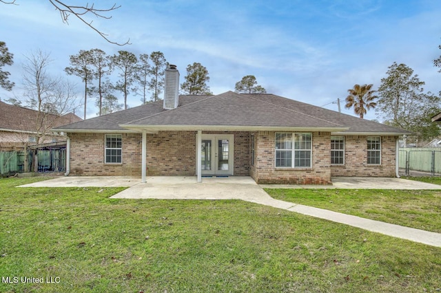 rear view of property with fence, a yard, a chimney, french doors, and a patio area