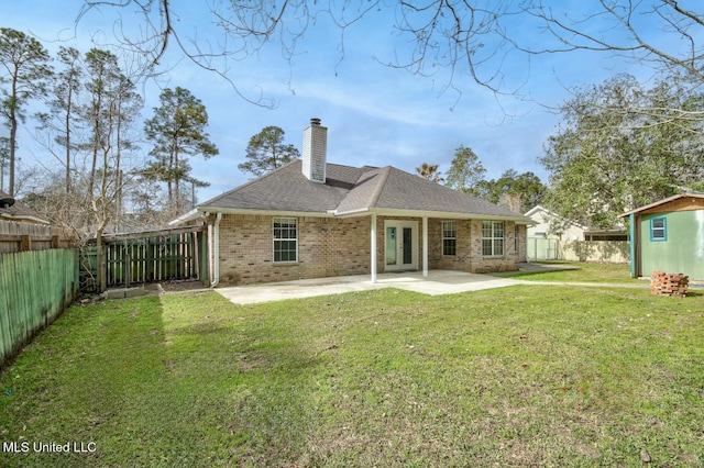 rear view of property with a fenced backyard, brick siding, a chimney, a patio area, and a lawn