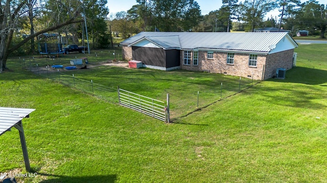 view of yard featuring a trampoline and central AC