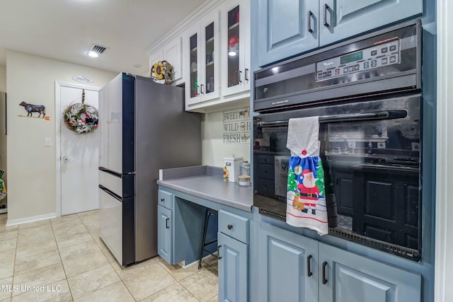 kitchen featuring white cabinets, stainless steel fridge, black oven, and light tile patterned flooring