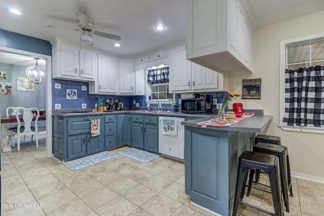 kitchen featuring white cabinetry, dishwasher, kitchen peninsula, a breakfast bar, and ceiling fan with notable chandelier