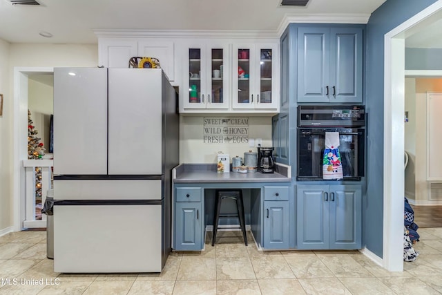 kitchen featuring black oven, white fridge, and blue cabinets