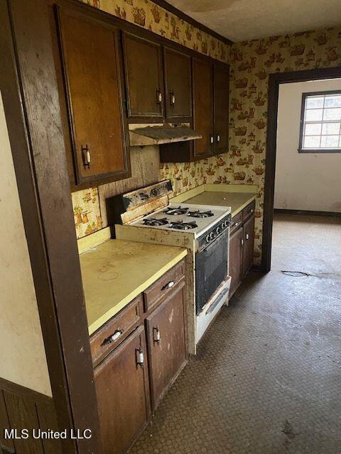 kitchen featuring dark brown cabinetry and white gas range oven