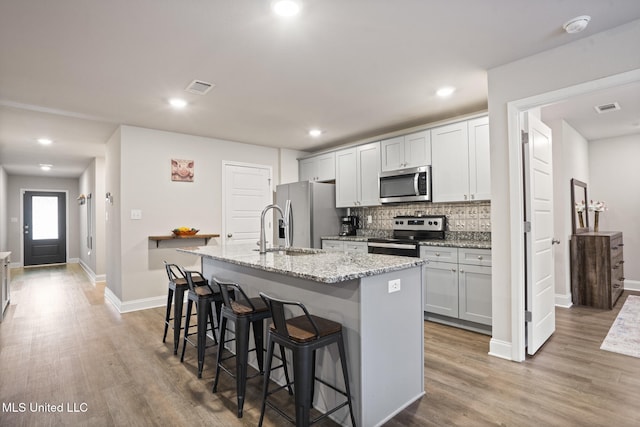 kitchen featuring an island with sink, visible vents, appliances with stainless steel finishes, and light wood-style flooring