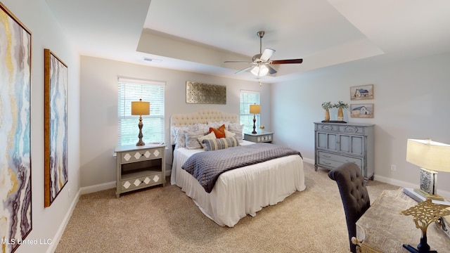 carpeted bedroom featuring ceiling fan and a raised ceiling