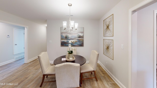 dining room with light hardwood / wood-style floors and a chandelier