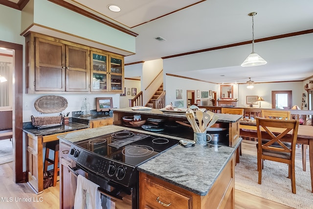 kitchen featuring black / electric stove, a kitchen island, and light wood-type flooring