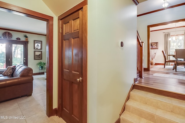 stairs with tile patterned floors, ornamental molding, and vaulted ceiling