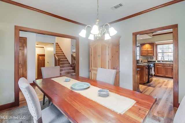 dining space with light hardwood / wood-style floors, an inviting chandelier, crown molding, and sink