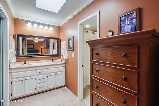 bathroom featuring vanity, a skylight, ceiling fan, and ornamental molding