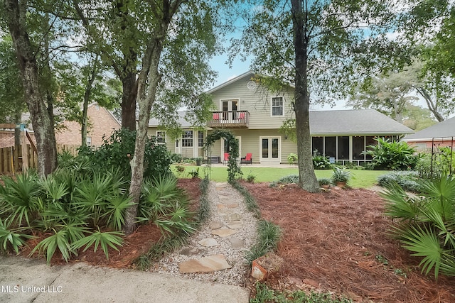 view of front of house featuring a sunroom, a balcony, and a front lawn