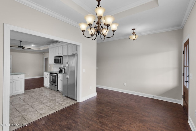 kitchen with stainless steel appliances, white cabinets, light countertops, a raised ceiling, and crown molding