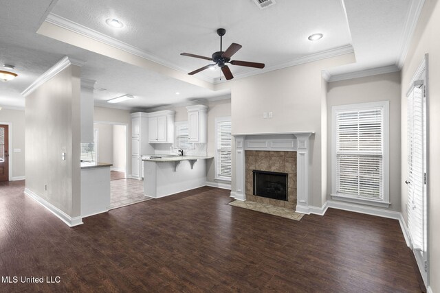 unfurnished living room with dark wood-style floors, a wealth of natural light, and a tiled fireplace