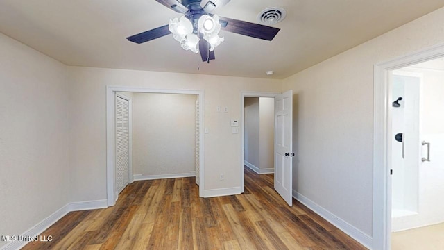 unfurnished bedroom with ceiling fan, wood finished floors, visible vents, baseboards, and a closet