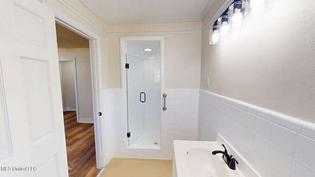 bathroom featuring tile walls, wainscoting, a shower stall, and wood finished floors