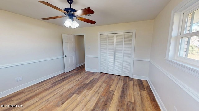 unfurnished bedroom with a closet, wood finished floors, a ceiling fan, and baseboards