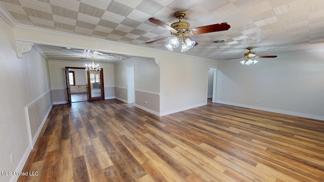 empty room featuring baseboards, visible vents, ornamental molding, and wood finished floors