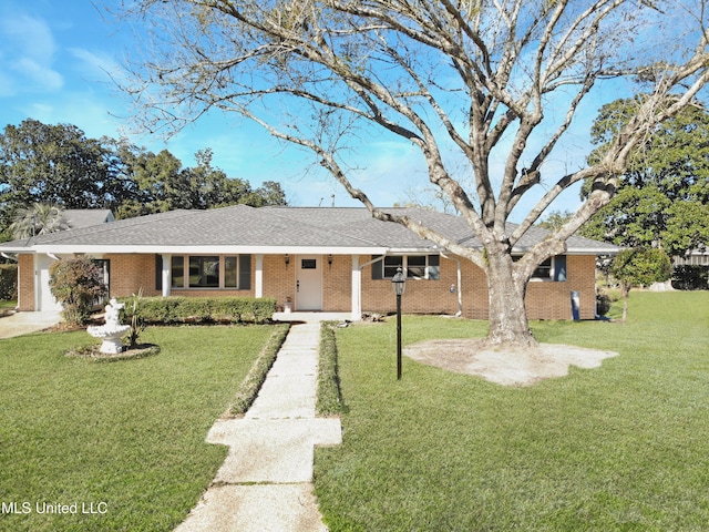 single story home with a shingled roof, a front yard, concrete driveway, and brick siding