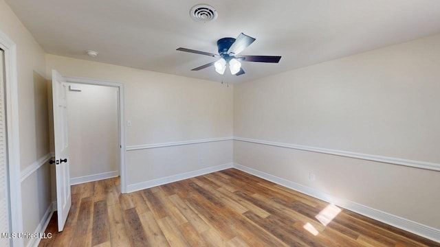 spare room with a ceiling fan, baseboards, visible vents, and wood finished floors