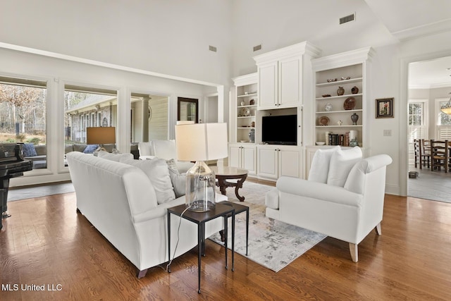 living area featuring a high ceiling, visible vents, and dark wood-type flooring