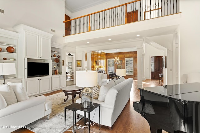 living room featuring ceiling fan with notable chandelier, wood finished floors, decorative columns, and crown molding