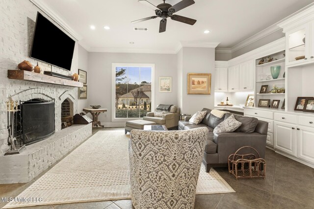 living room with a fireplace, visible vents, ornamental molding, a ceiling fan, and dark tile patterned floors