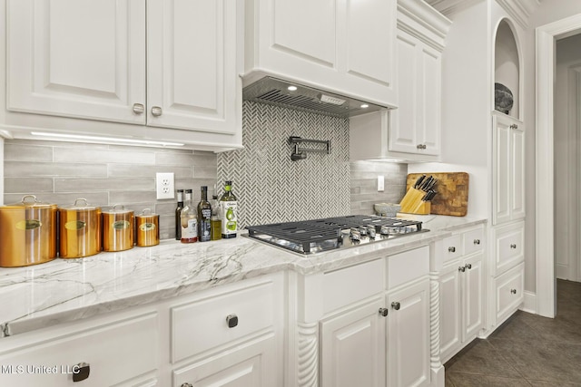 kitchen featuring dark tile patterned flooring, custom exhaust hood, white cabinetry, and stainless steel gas stovetop