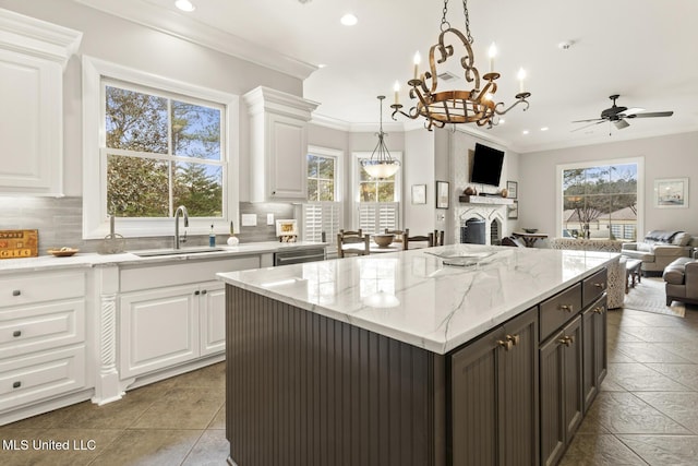 kitchen featuring ornamental molding, open floor plan, a sink, white cabinetry, and backsplash